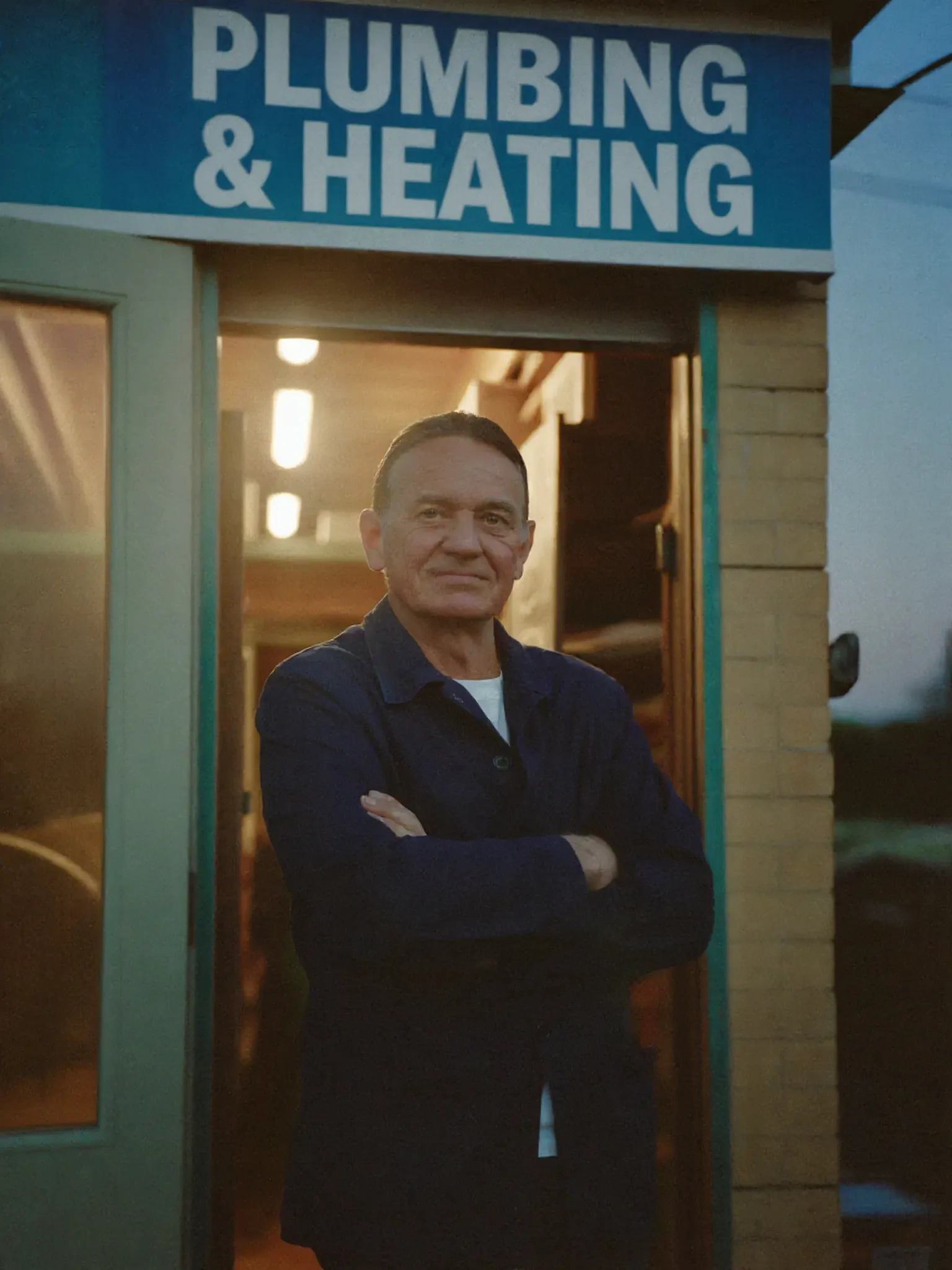 A proud Irish plumber at his workshop doorway at dusk
